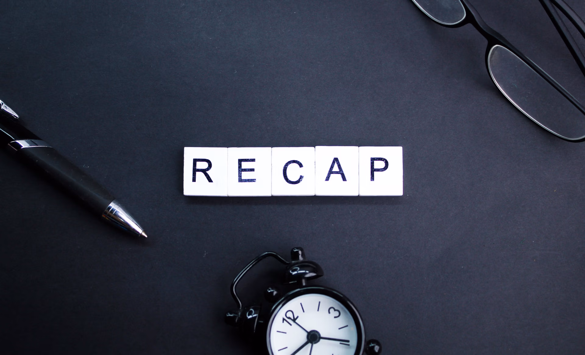 glasses, pen and bell clock with letters of the alphabet or the word recap